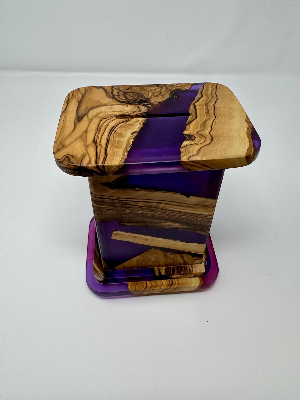 Handmade Israeli olive wood and violet epoxy tzedakah box – three-quarter view showing lid, tapered body and raised base