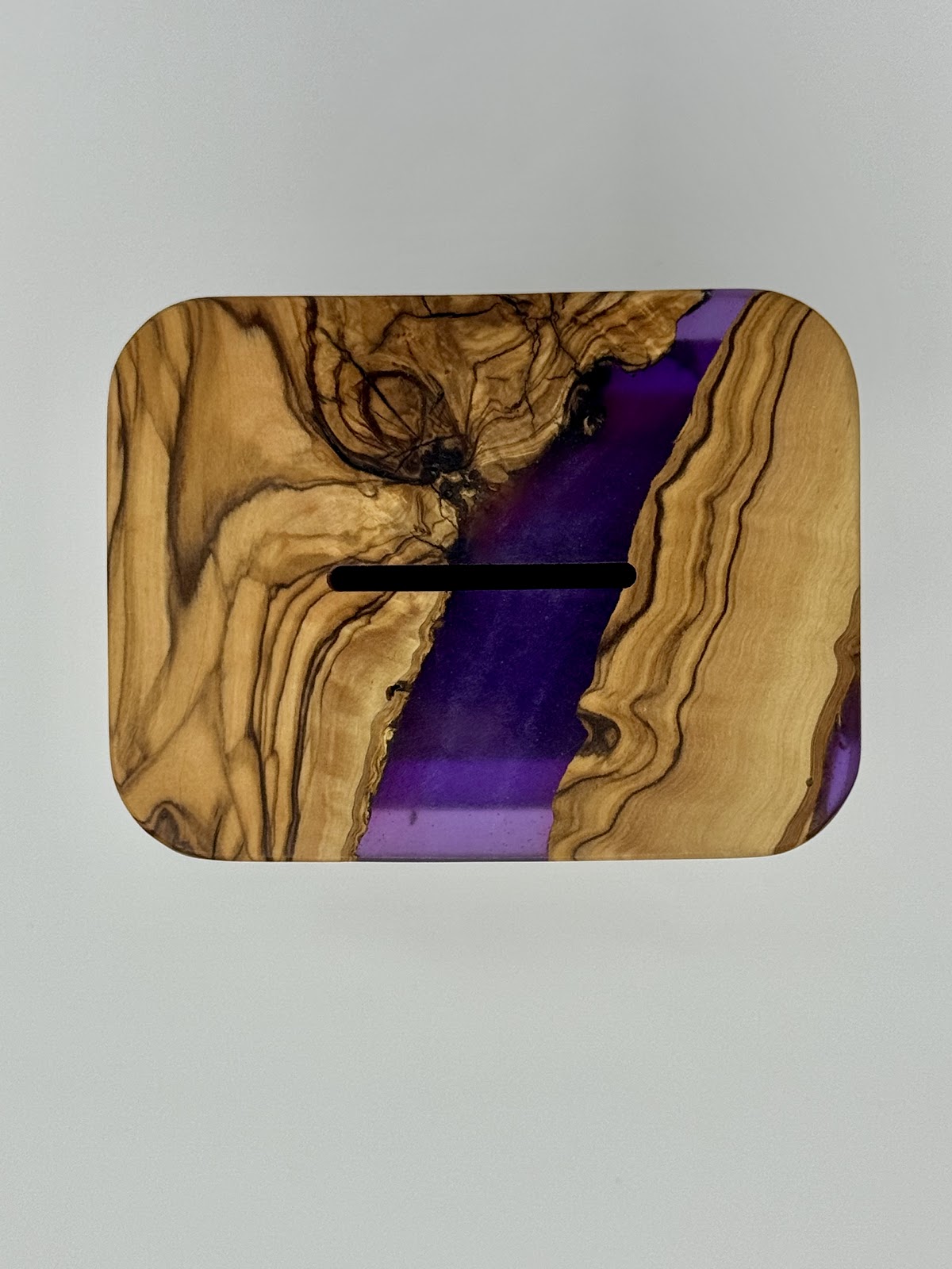 Top view of handmade olive wood tzedakah box lid with coin slot and violet epoxy