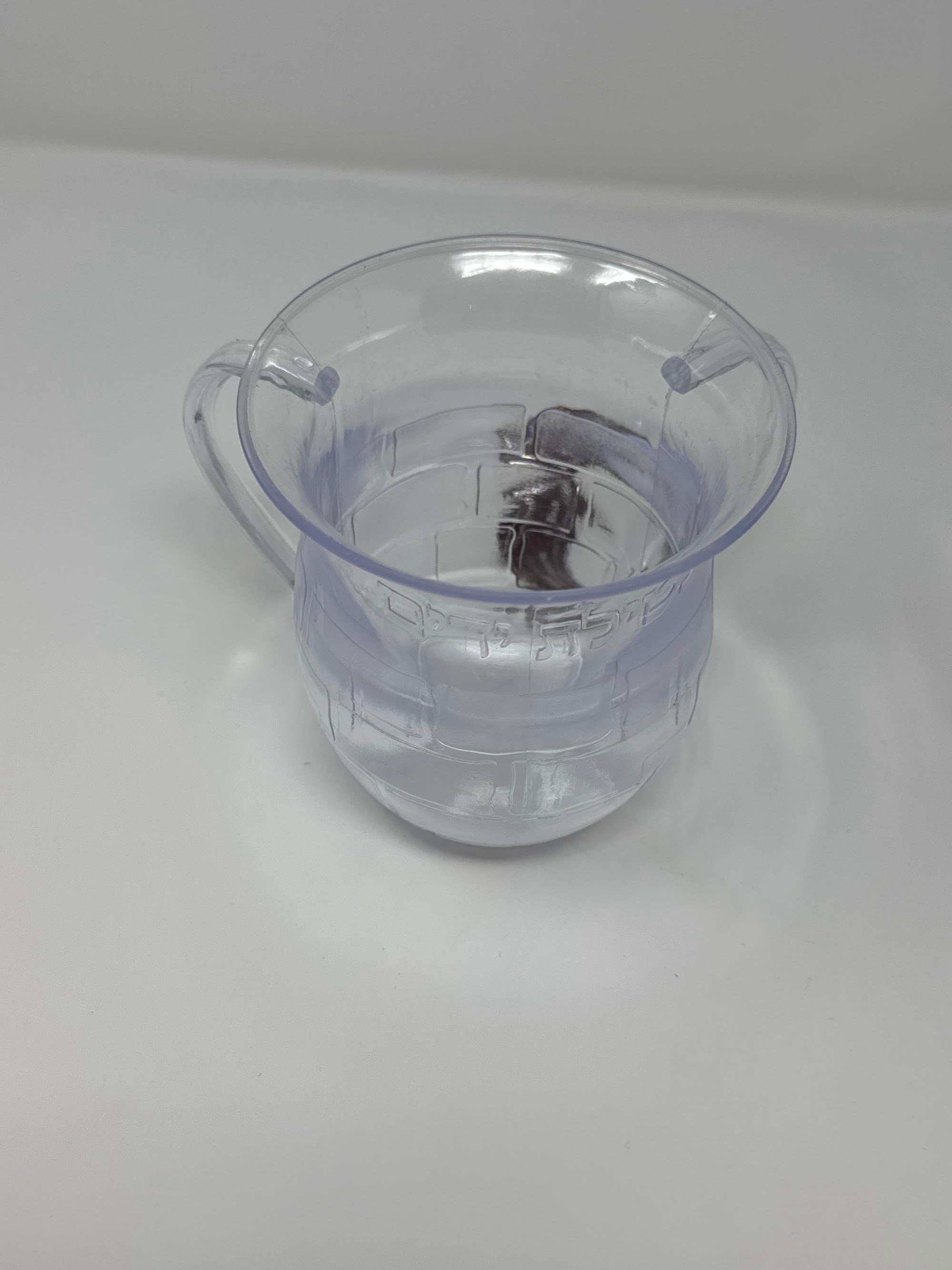Clear Kotel washing cup, angled view showing the raised blessing | MitzvahArt