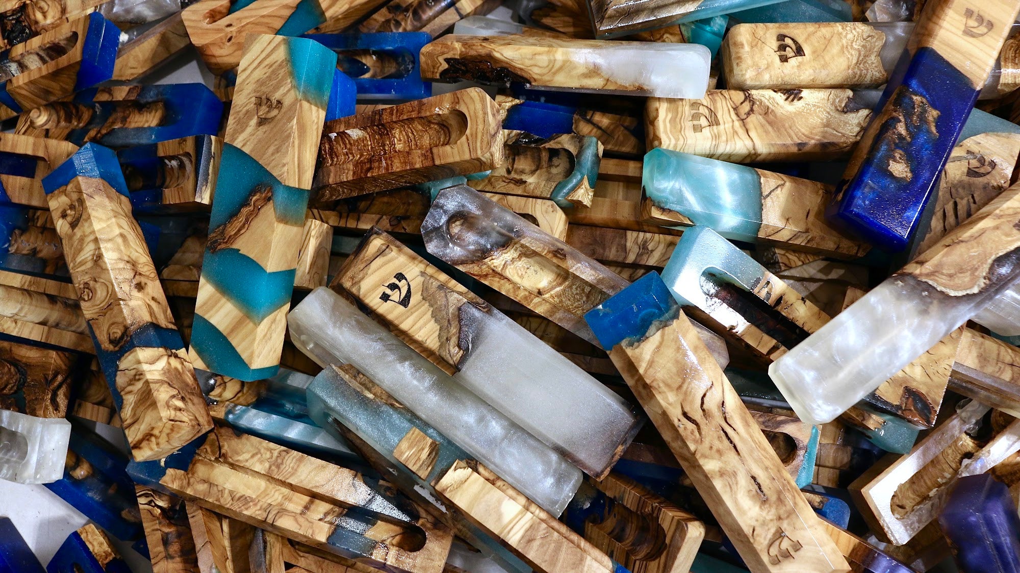 Handmade olive wood and resin mezuzah cases gathered together, no two alike | MitzvahArt